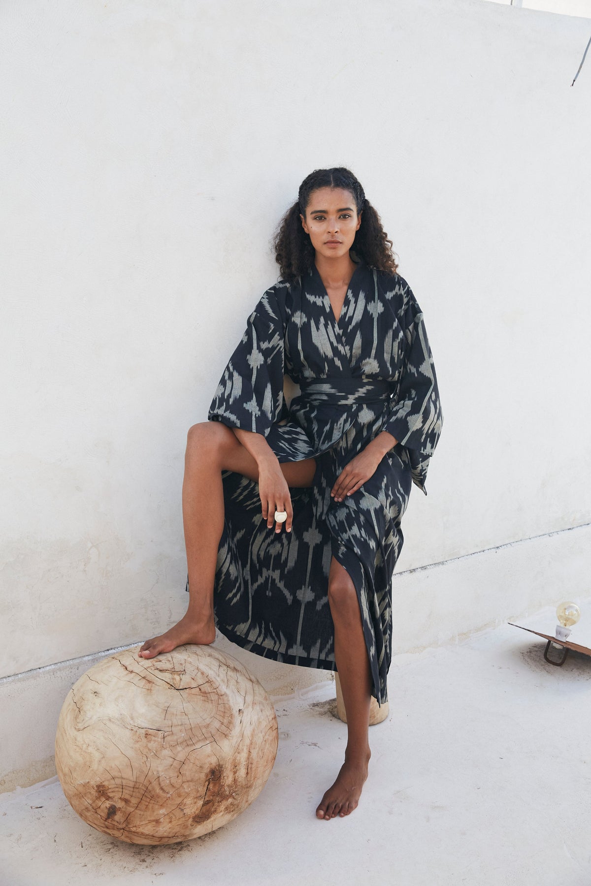Woman wearing Kleed Congo Naya Kimono in handloomed Ikat cotton black and khaki seated outdoors sustainable conscious luxury