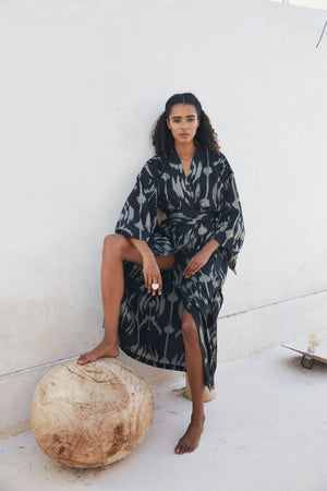 Woman wearing Kleed Congo Naya Kimono in handloomed Ikat cotton black and khaki seated outdoors sustainable conscious luxury