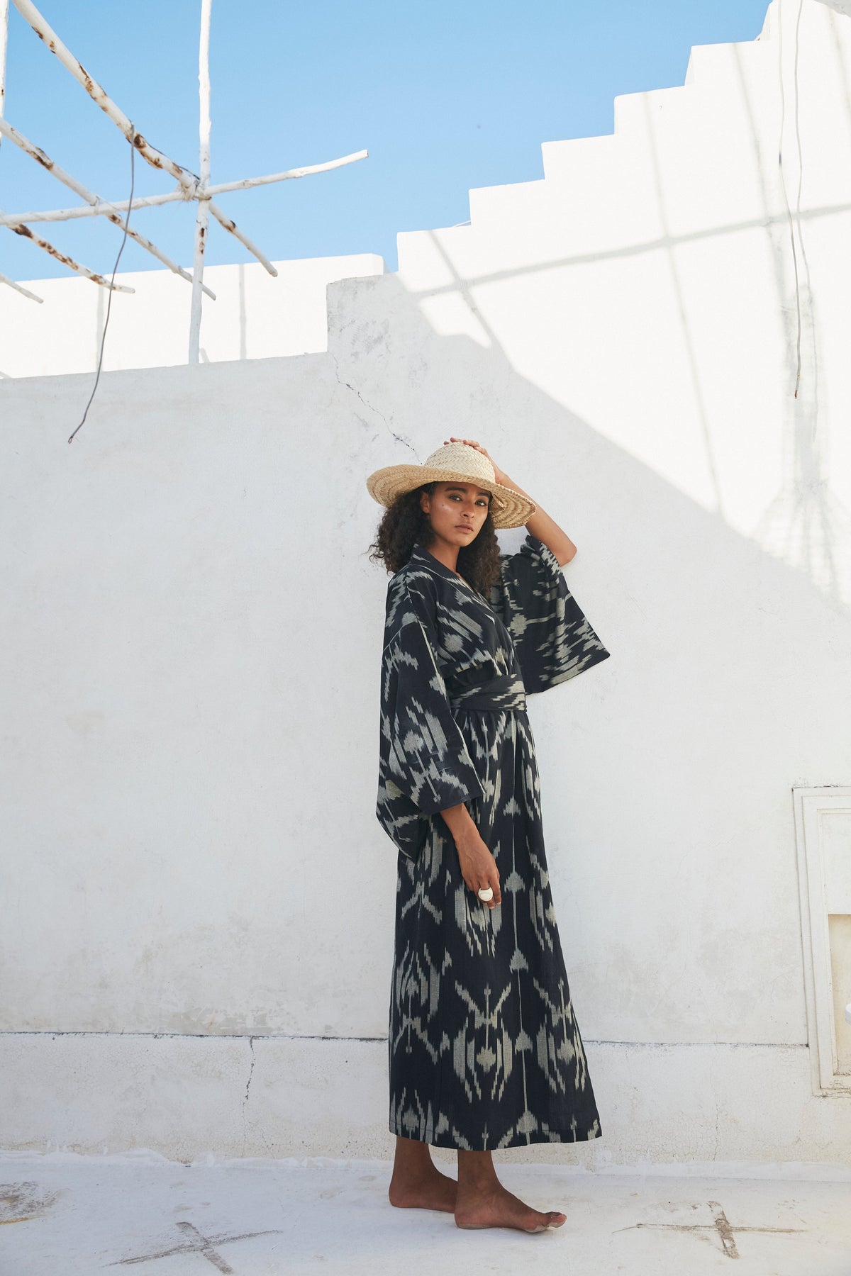 Woman wearing Kleed Congo Naya Kimono in handloomed Ikat cotton black and khaki pattern standing against white wall