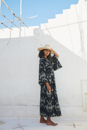 Woman wearing Kleed Congo Naya Kimono in handloomed Ikat cotton black and khaki pattern standing against white wall
