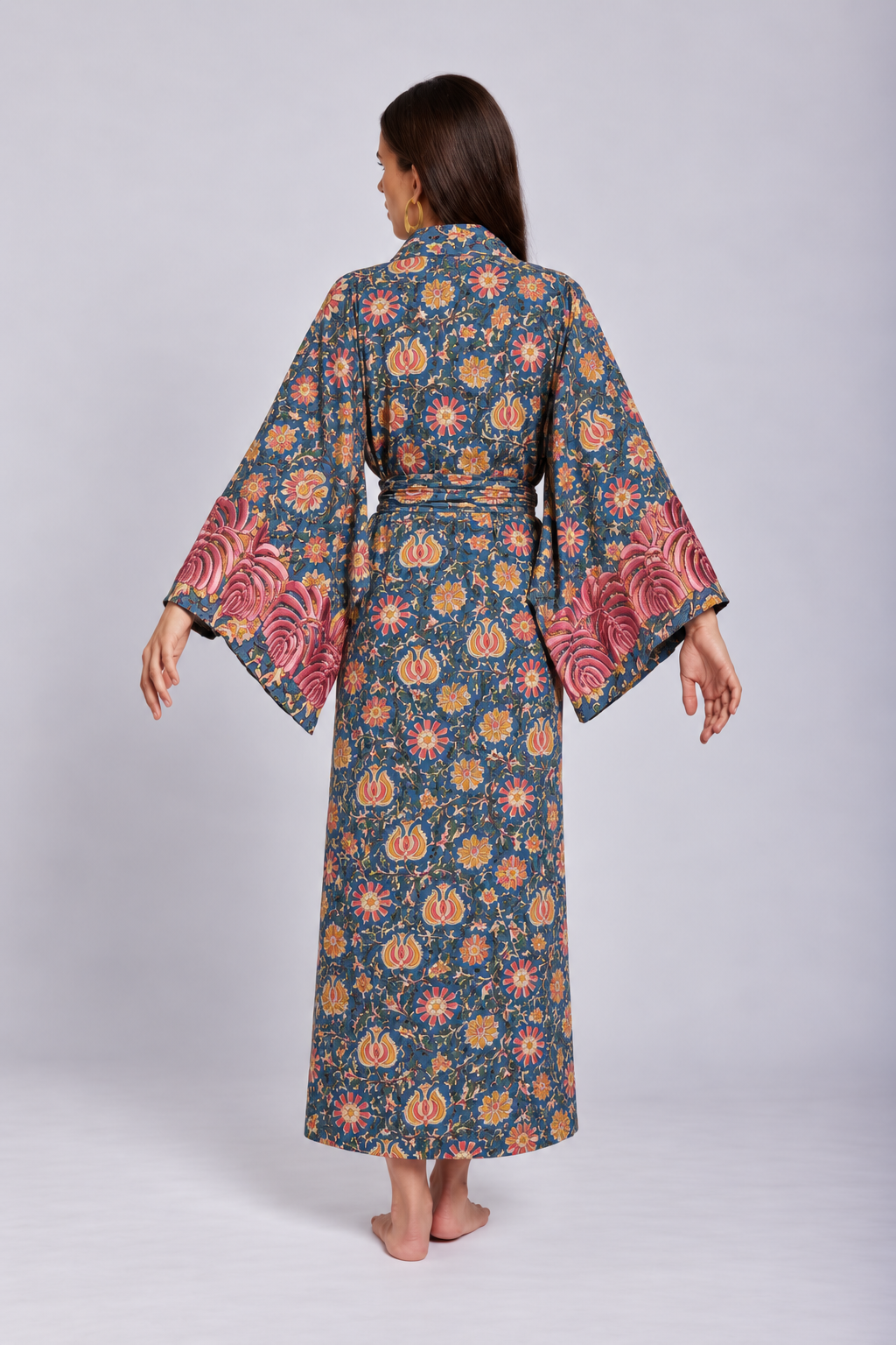 Back view of model wearing the Gulab Kimono from KLEED, a long cotton kimono for women, hand block printed with floral motifs and detailed pink sleeve embroidery.