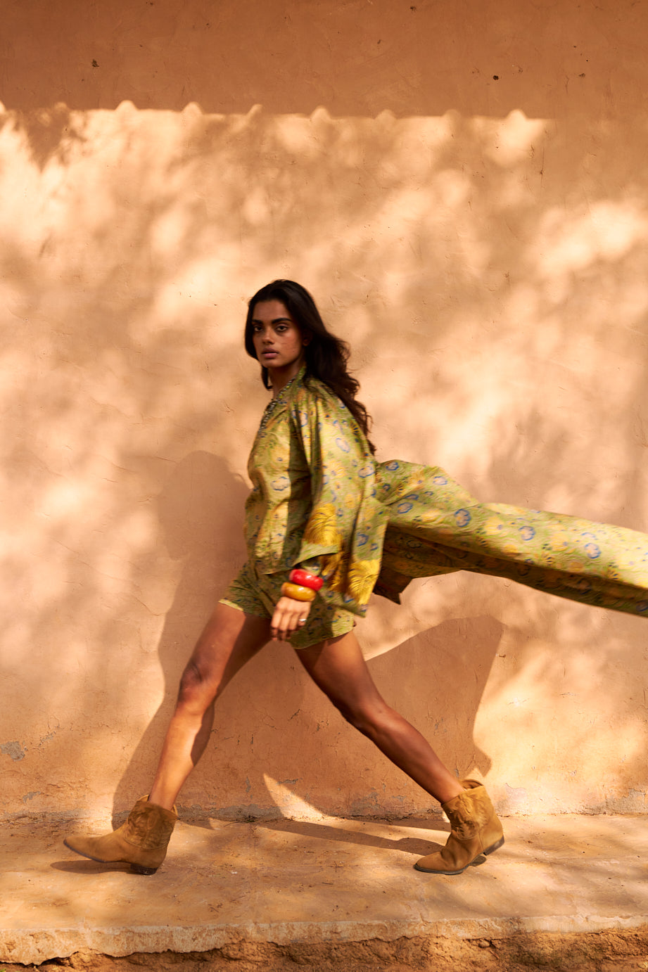 Model in the Kleed Jasmine Kimono in motion, photographed in a sunlit desert landscape and hankle caramel boots and red caramel bangles.