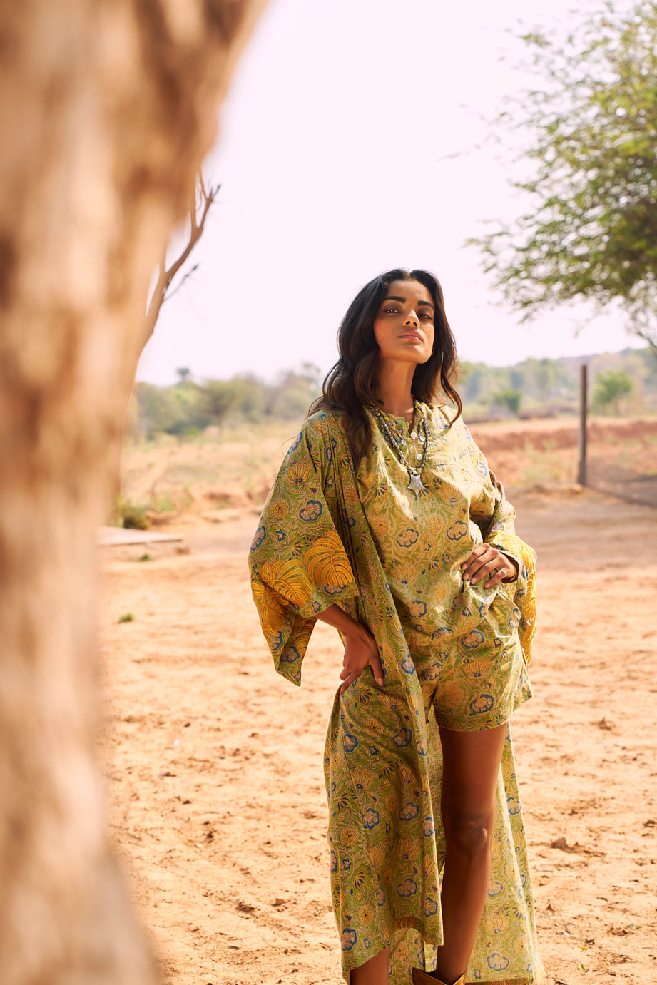 Model wearing the Kleed Jasmine Kimono long kimono in olive yellow with hand block printed flower motifs, full-length editorial shot