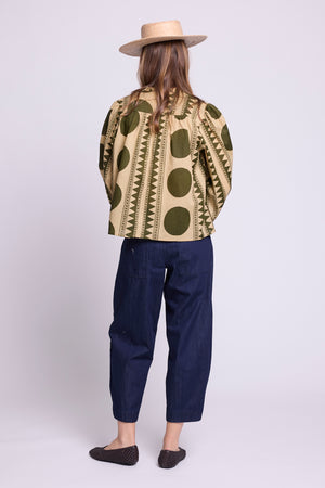 Model wearing the KLEED Khaki Geo Balloon Shirt in 100% cotton, back view styled with dark blue cropped trousers and a straw hat.