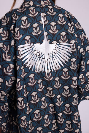 Close up of krisant naya kimono, from Kleed in 100% hand block printed cotton. Black with blue and white flower motifs. Embroidered crane at the back.