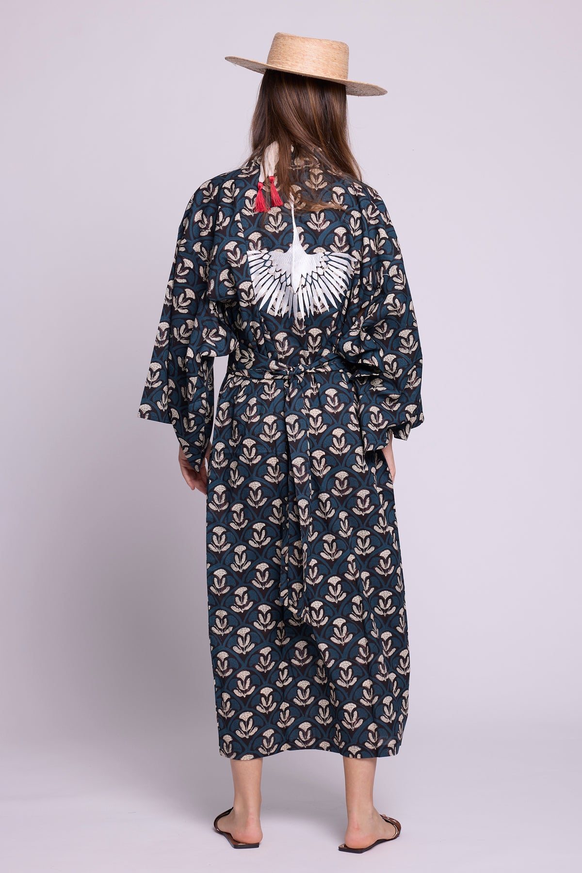 Back view of model wearing krisant naya kimono from Kleed. 100% hand blockprinted cotton, Flower motifs in blue white and black. Flat sandals.