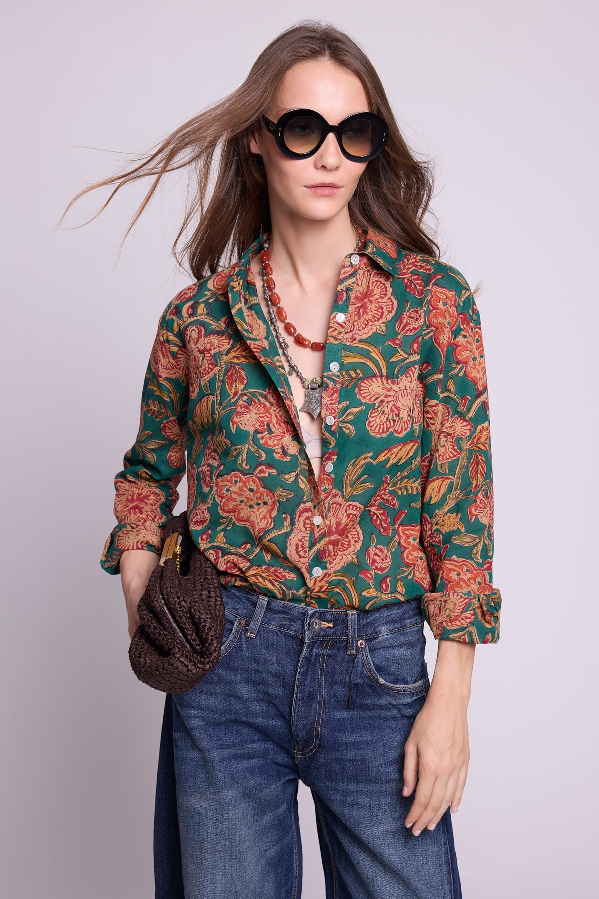 KLEED Lotus Green Shirt, women’s cotton shirt in 100% hand block printed cotton with a rich green floral print, mother-of-pearl buttons and relaxed fit, styled with wide-leg denim, oversized sunglasses, layered necklaces and a textured dark bag in a close-up studio fashion photo.