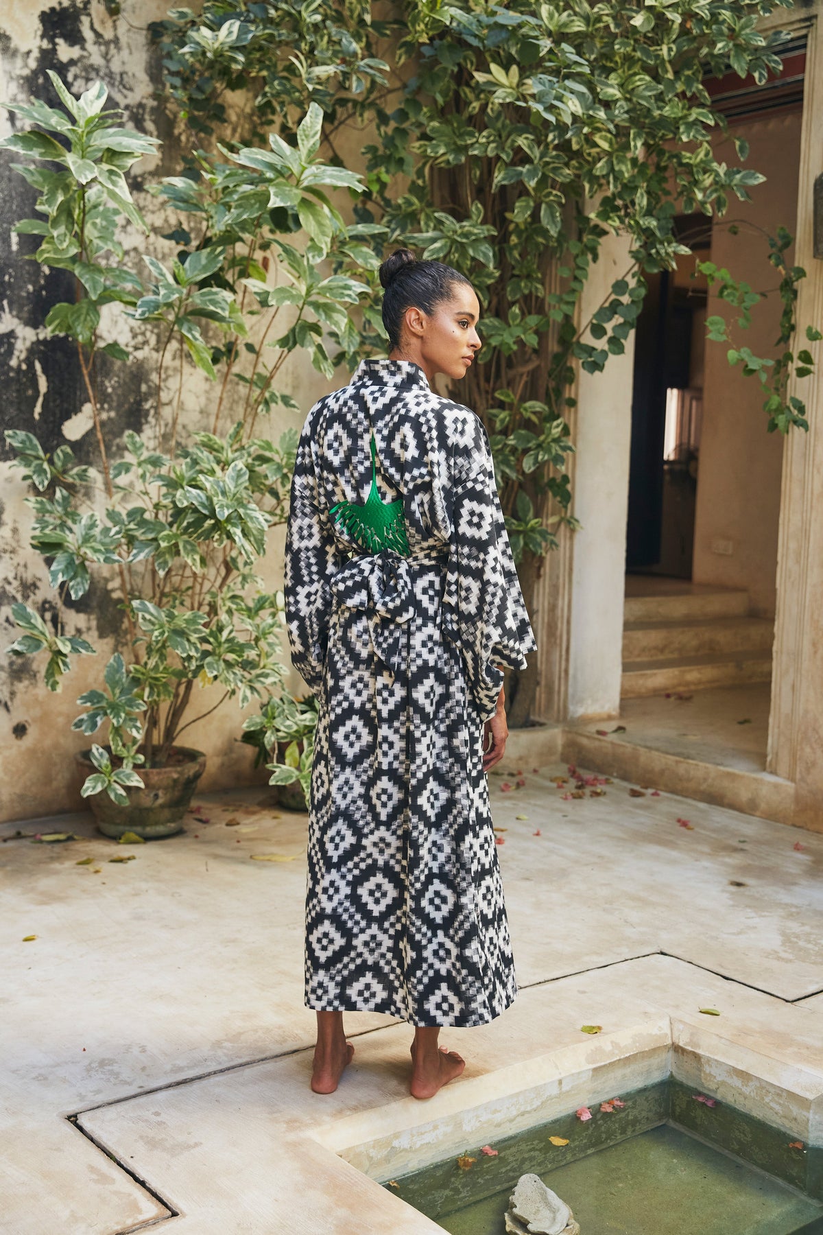 Woman wearing Kleed Mombasa Black Kimono in handloomed Ikat cotton black and white geometric pattern standing in courtyard