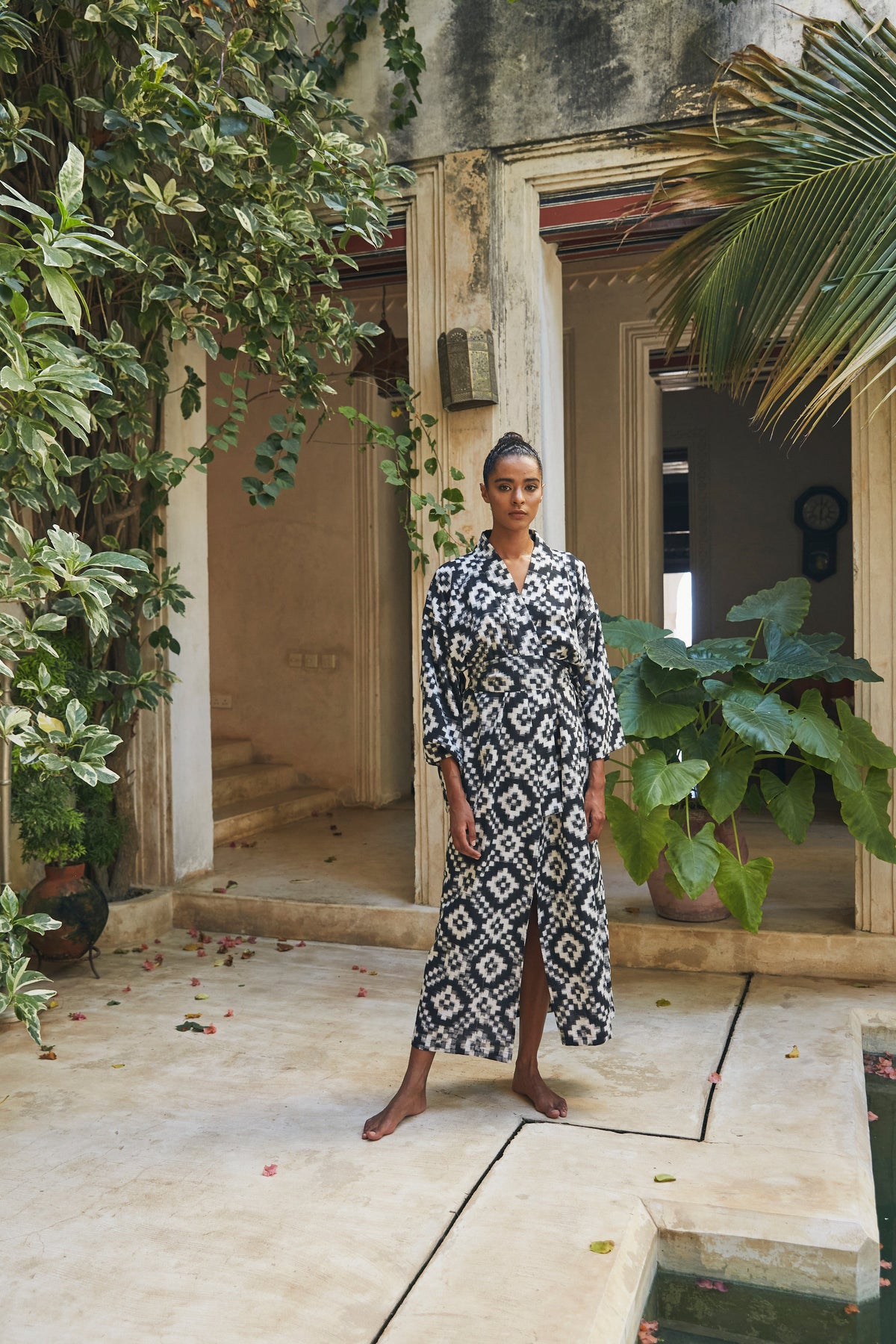 Woman wearing Kleed Mombasa Black Kimono in handloomed Ikat cotton black and white geometric pattern outdoor courtyard full length