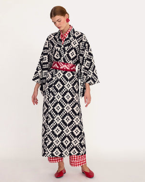 Woman wearing Kleed Mombasa Black Kimono in handloomed Ikat cotton black and white geometric pattern side with red vichy pyjama underneath
