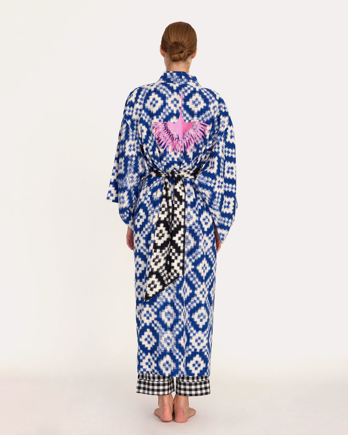 Back view of woman wearing Kleed Mombasa Blue Kimono handwoven Ikat cotton blue and white with pink crane hand embroidery