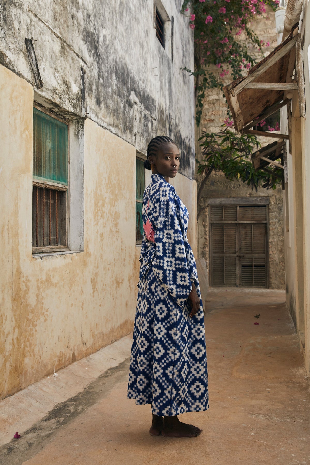 Woman wearing Kleed Mombasa Blue Kimono in handwoven Ikat cotton blue and white geometric pattern outdoor ancient wall editorial