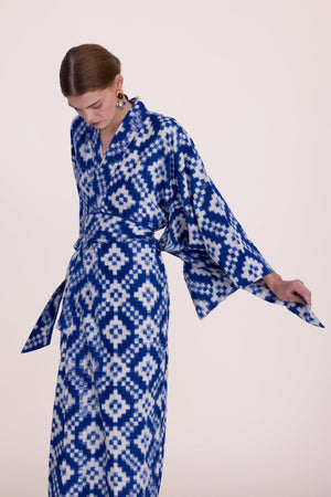 Woman wearing Kleed Mombasa Blue Kimono in handwoven Ikat cotton blue and white geometric pattern side view looking down studio