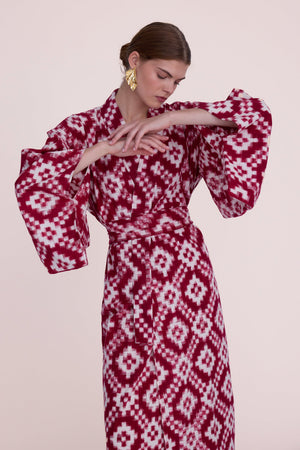 Woman wearing Mombasa red Ikat cotton kimono by Kleed, close-up detail of wide dramatic sleeves with gold leaf earrings, handcrafted sustainable loungewear
