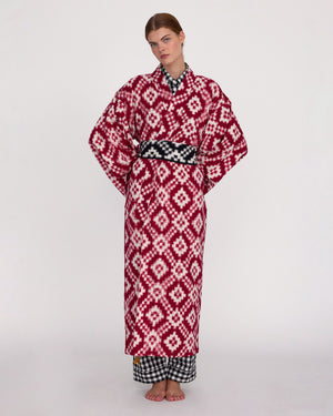 Front side of the Mombasa red Ikat cotton kimono by Kleed styled with black and white gingham belt and trousers, full length studio shot, handcrafted sustainable loungewear