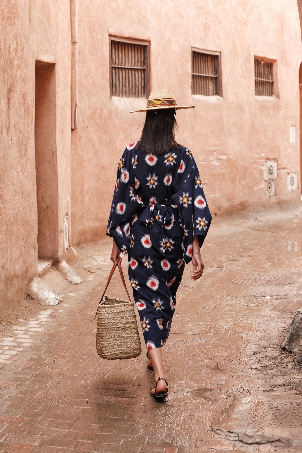 Woman walking away wearing Kleed Sushi Kimono in handloomed Ikat cotton navy blue geometric pattern in red yellow and white