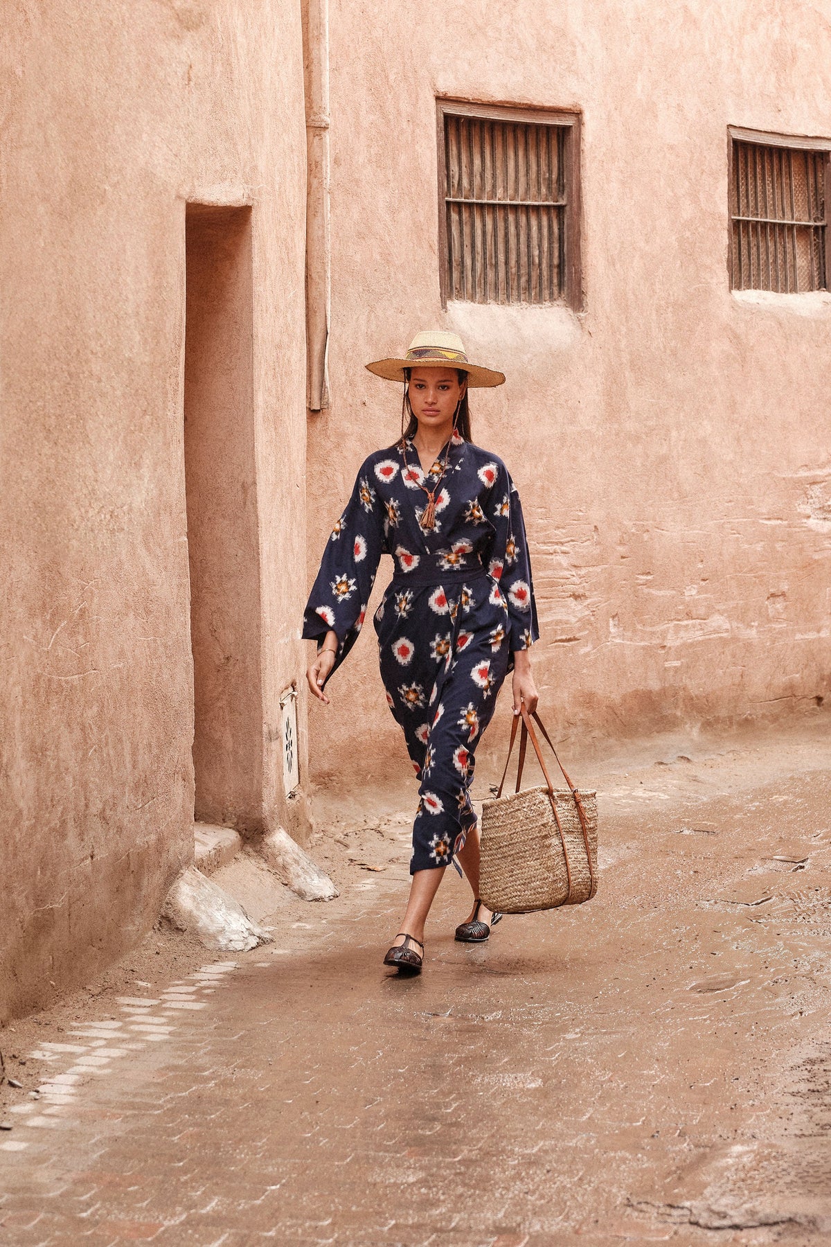 Woman walking in medina wearing Kleed Sushi Kimono in handloomed Ikat cotton navy blue geometric pattern in red yellow and white